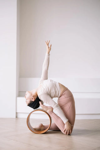 Annette Chan performing a Camel Pose variation using a yoga wheel for deep backbend support